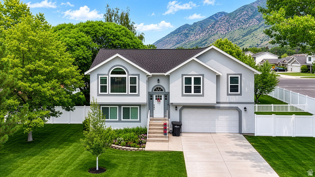 464 West Saddle Back Drive Springville, UT 84663 - Photo 1 of 15 Split-level residence featuring a two-car garage, white privacy fencing, and mature landscaping