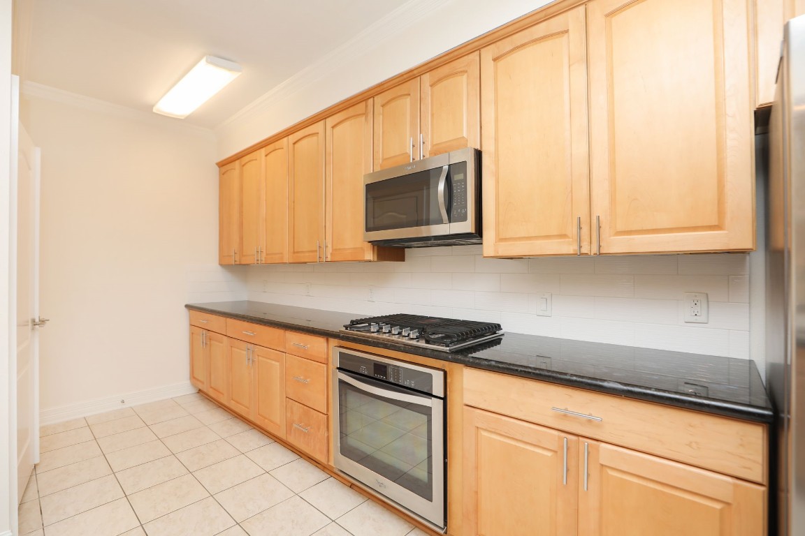 7499 Brompton Street, Unit 7499 Houston, TX 77025 - Photo 19 of 43 a kitchen with stainless steel appliances granite countertop white cabinets and a stove top oven