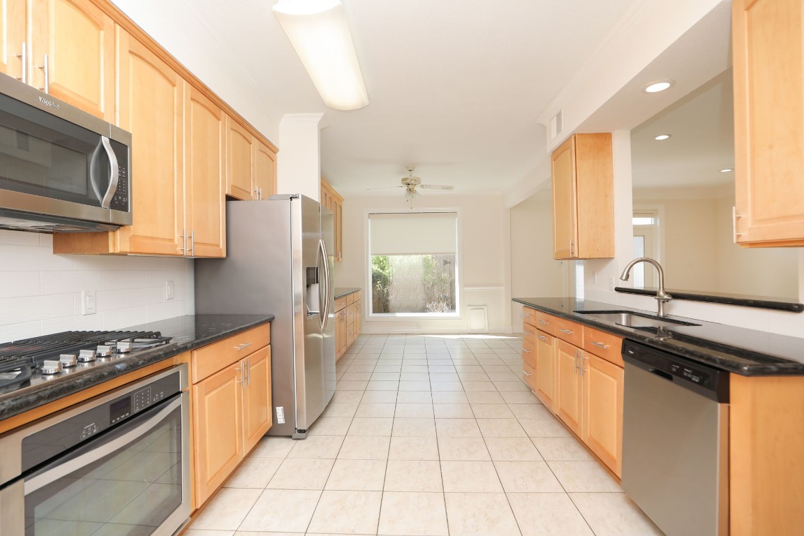 7499 Brompton Street, Unit 7499 Houston, TX 77025 - Photo 21 of 43 a kitchen with stainless steel appliances granite countertop a stove top oven a sink dishwasher and a refrigerator with wooden cabinets