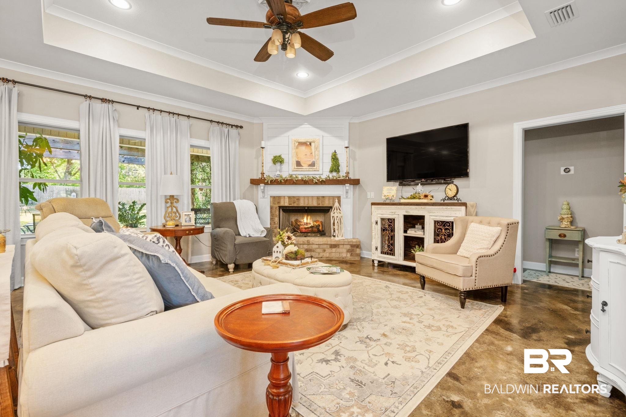 4331 Hamilton Oaks Lane Mobile, AL 36695 - Photo 5 of 38 Living room featuring a raised ceiling, ceiling fan, a warm lit fireplace, ornamental molding, and baseboards