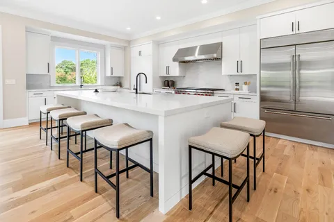 a kitchen with stainless steel appliances a sink and chairs
