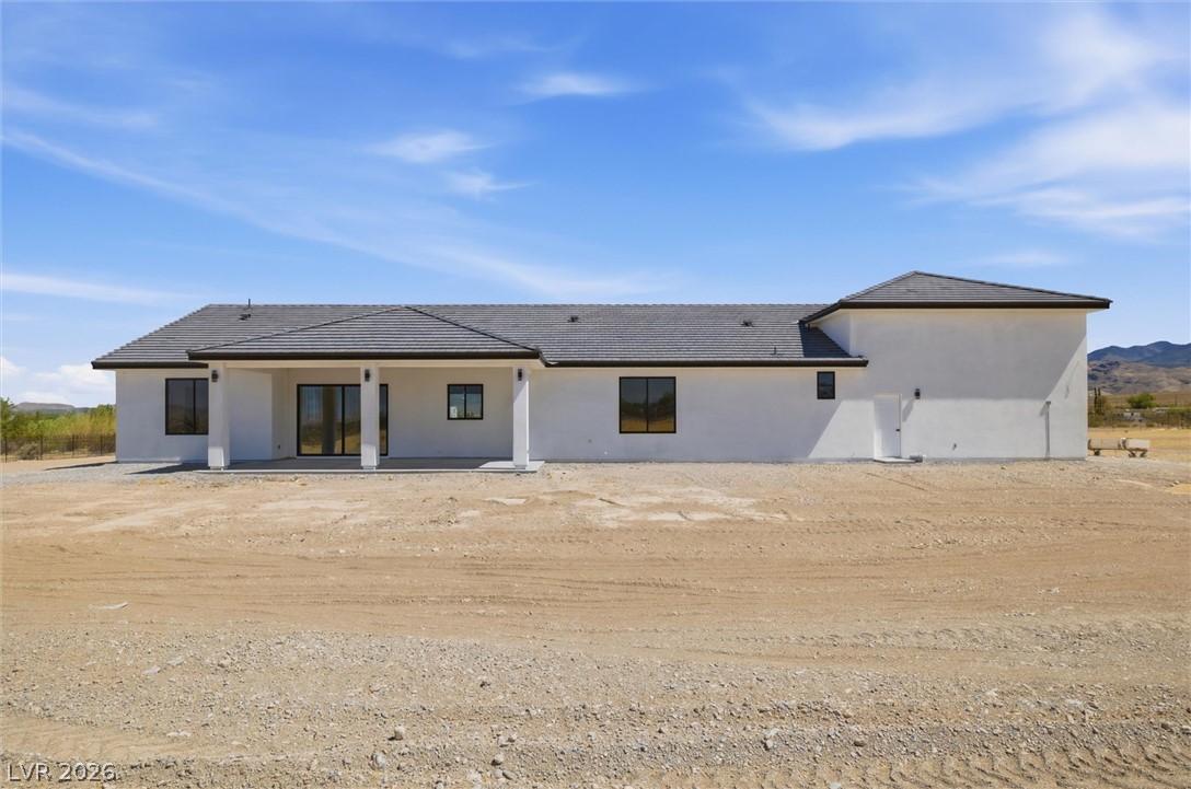 5910 East Kellogg Road Pahrump, NV 89061 - Photo 44 of 58 A newly constructed residence features a crisp white stucco exterior, dark window frames, and a durable tile roof.