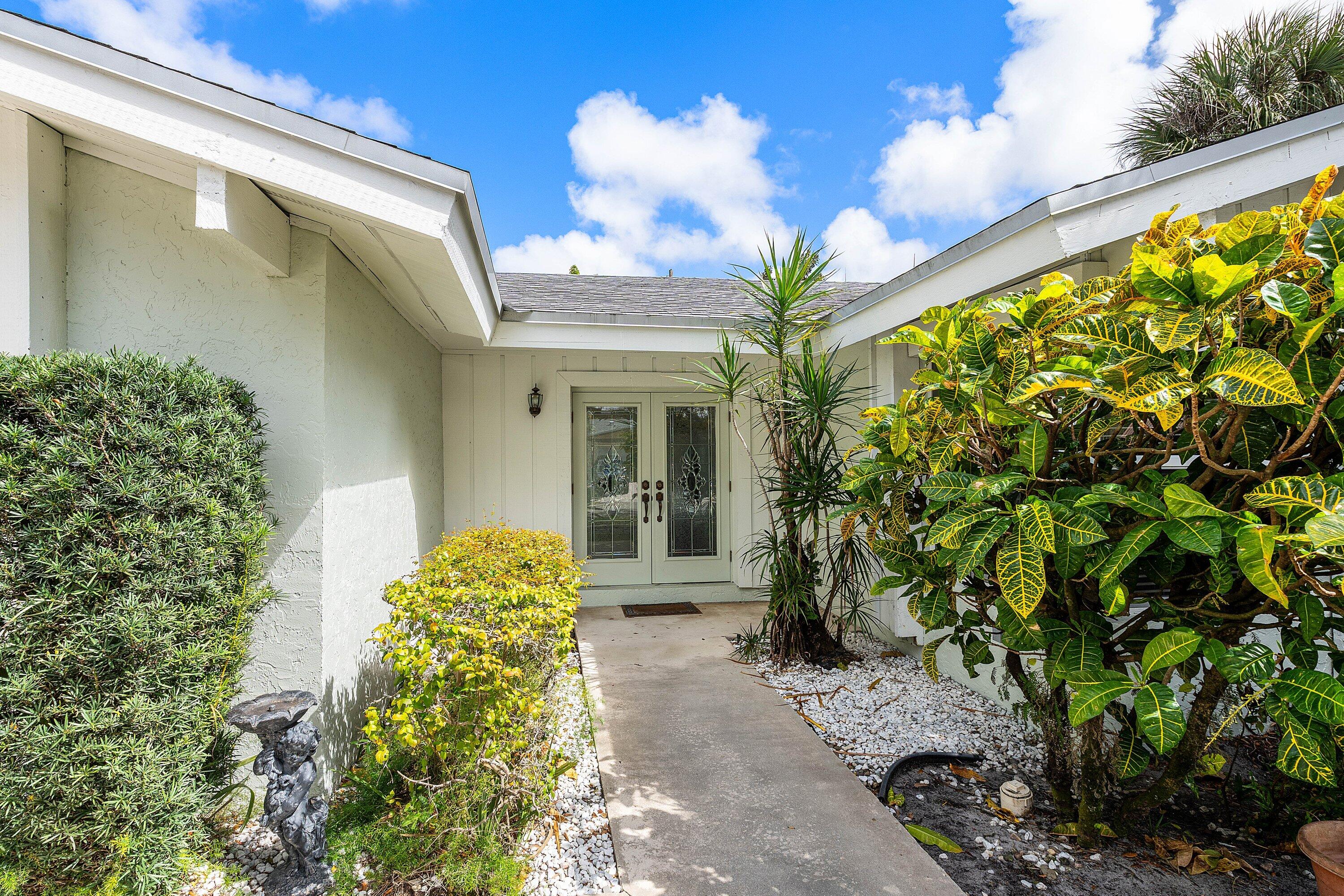 3068 Northwest 25th Way Boca Raton, FL 33434 - Photo 4 of 43 a yellow house with a yard and garden