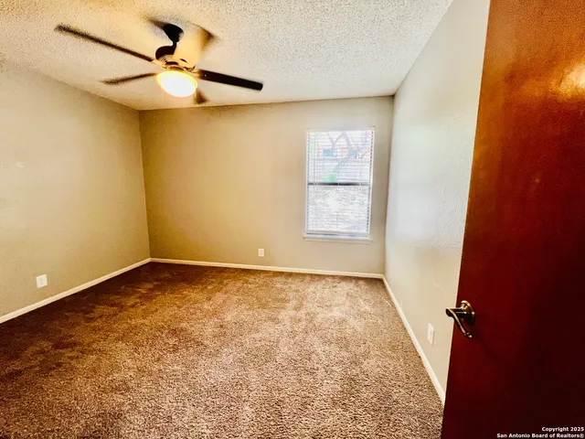 an empty room with a window and a fan