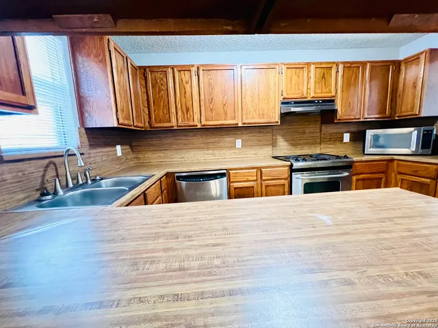 a kitchen with stainless steel appliances granite countertop wooden cabinets a stove top oven a sink and dishwasher