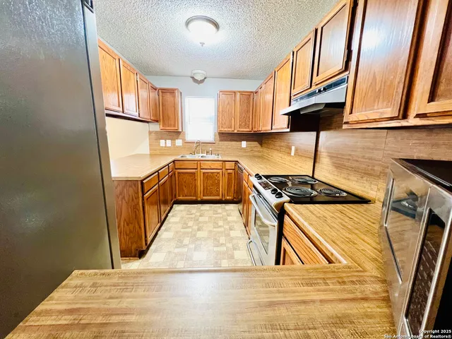 a kitchen with stainless steel appliances granite countertop a sink a stove and a refrigerator