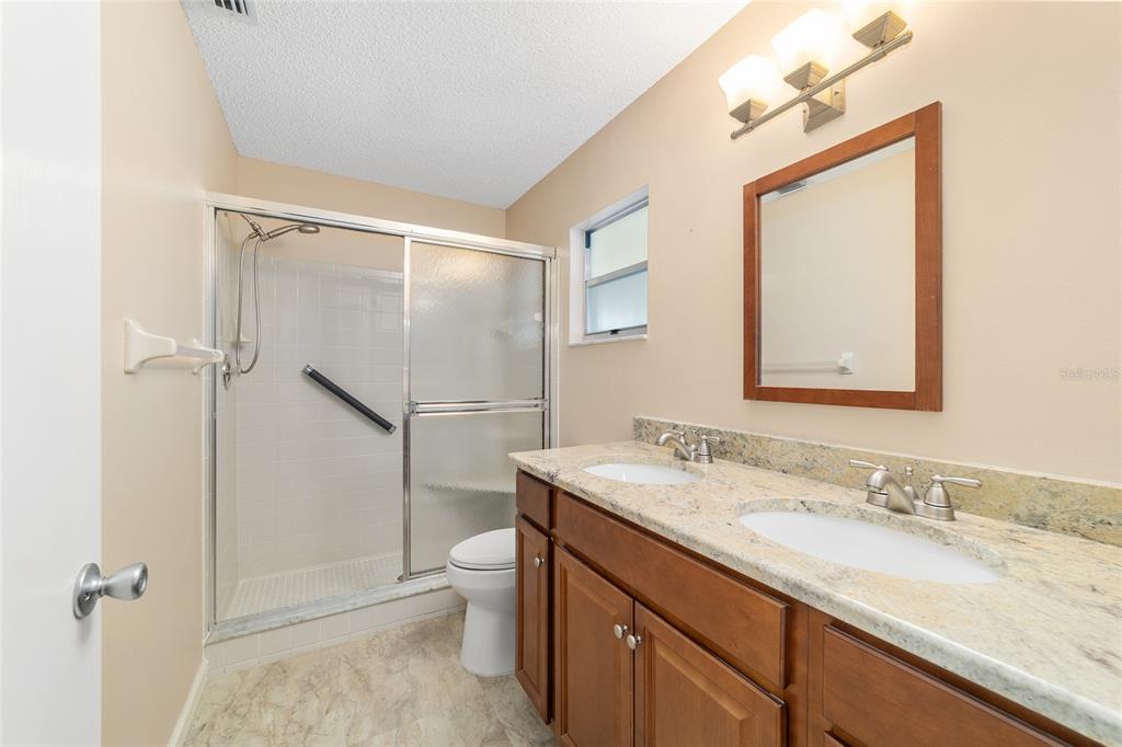 9240 Southwest 90th Court, Unit B Ocala, FL 34481 - Photo 31 of 40 a bathroom with a granite countertop sink mirror vanity and toilet