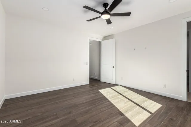 an empty room with wooden floor and a ceiling fan