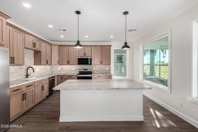 a kitchen with stainless steel appliances granite countertop a sink a stove and a refrigerator