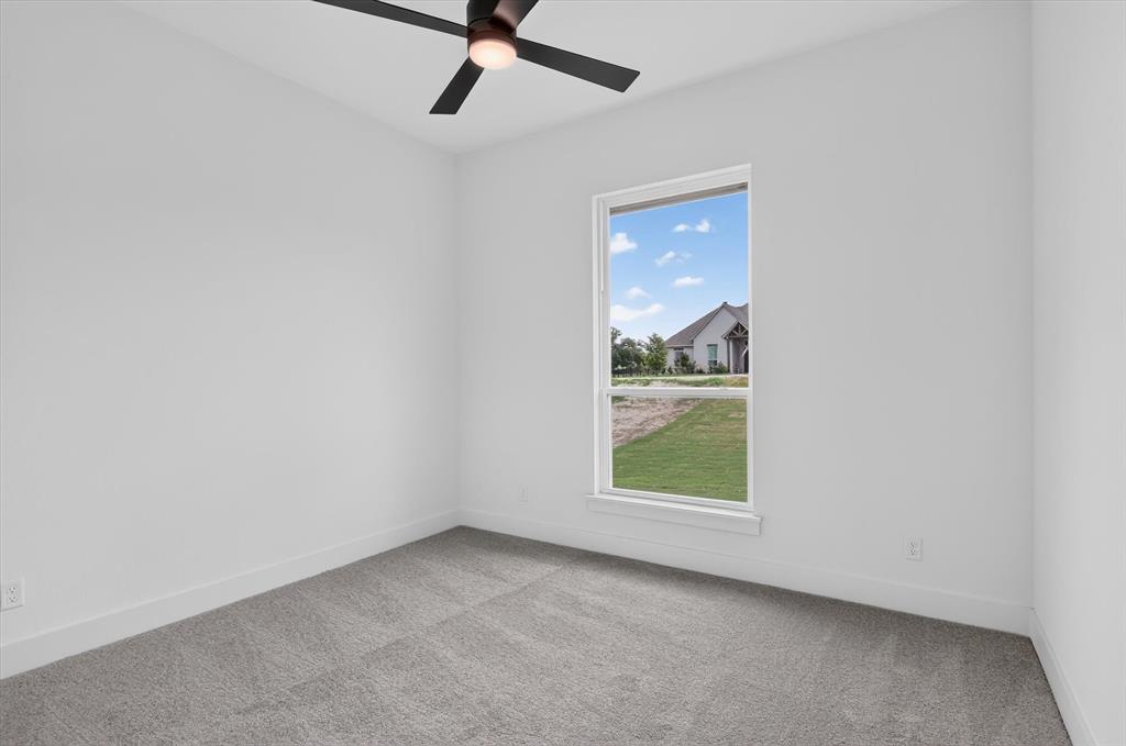 471 Red Bird Drive Springtown, TX 76082 - Photo 27 of 35 Carpeted room featuring a ceiling fan with integrated lighting, a large window, white baseboards, and neutral wall tones