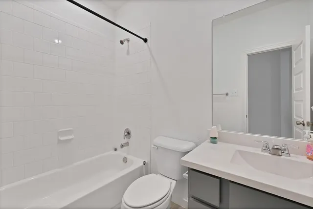 a bathroom with a bathtub shower sink vanity mirror and toilet