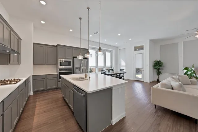 a large kitchen with kitchen island a large counter top space a sink stainless steel appliances and cabinets