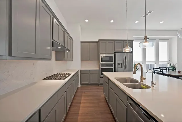 a kitchen with stainless steel appliances granite countertop a sink a stove and a refrigerator