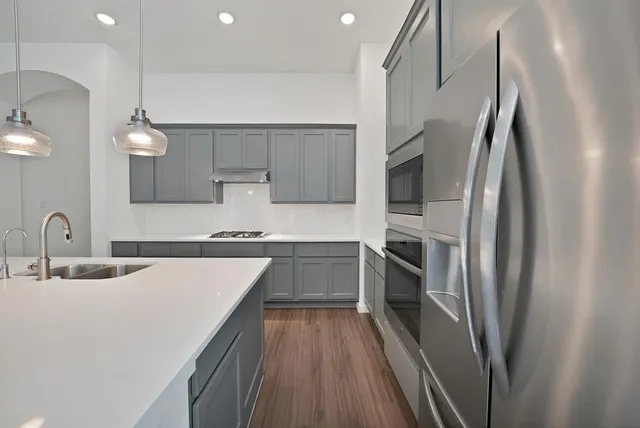 a kitchen with kitchen island a counter top space a sink stainless steel appliances and cabinets