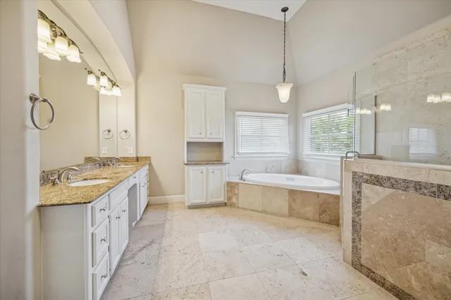 a bathroom with a granite countertop sink a large mirror and a bathtub