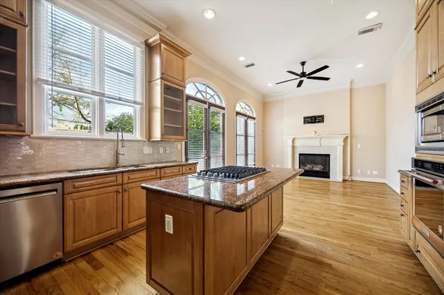 a kitchen with stainless steel appliances granite countertop a sink a stove and a wooden floors