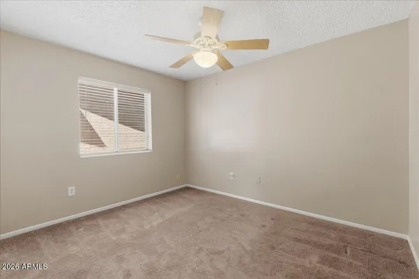 an empty room with a window and a fan