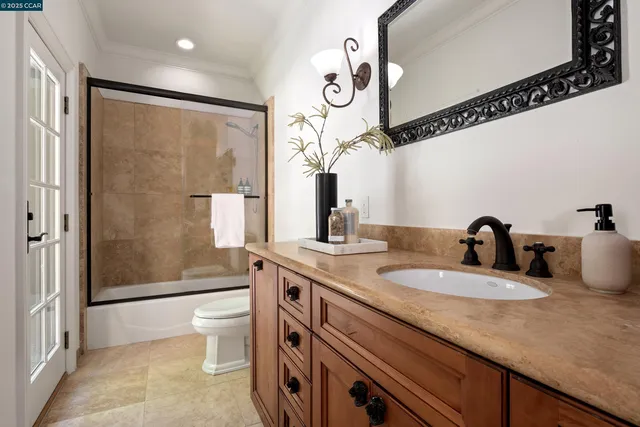 a bathroom with a granite countertop sink a toilet a mirror and shower