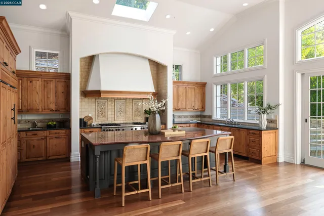 a kitchen with stainless steel appliances granite countertop table chairs stove and wooden floor