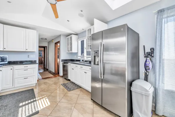 a kitchen with stainless steel appliances granite countertop a refrigerator a sink and white cabinets