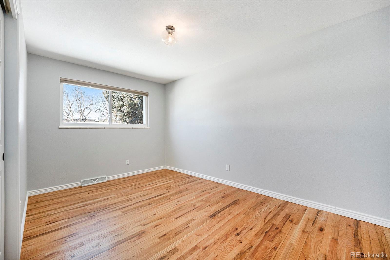 3582 Wright Street Wheat Ridge, CO 80033 - Photo 18 of 31 an empty room with wooden floor and windows
