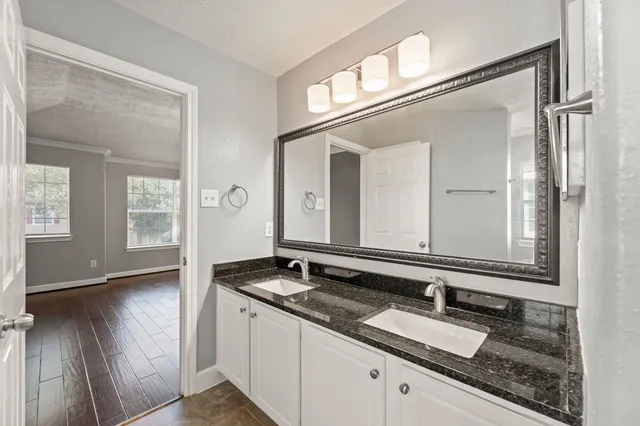a bathroom with a granite countertop double vanity sink and a mirror