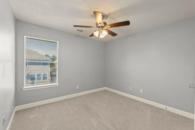 an empty room with a window and a fan