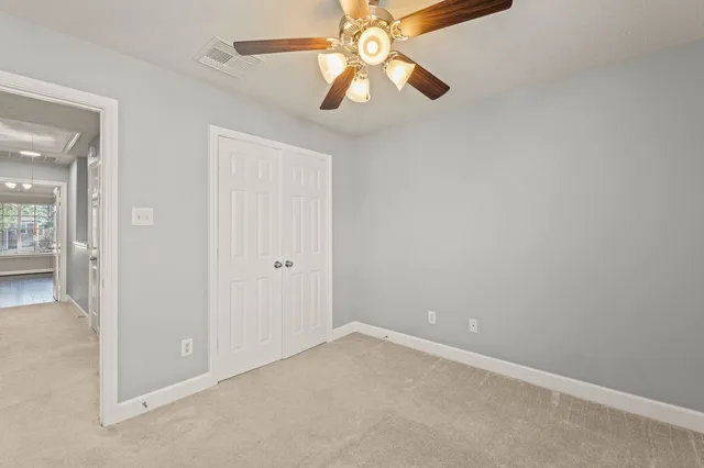 a view of an empty room and chandelier fan