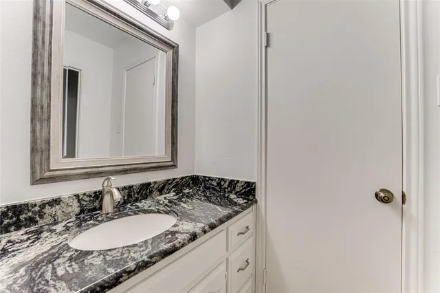a bathroom with a granite countertop sink and a mirror