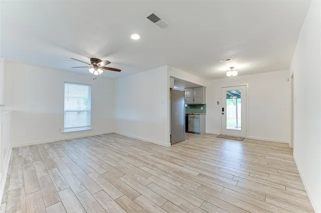 an empty room with wooden floor closet and windows