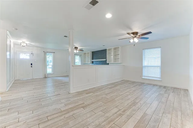 a view of an empty room with a window and wooden floor