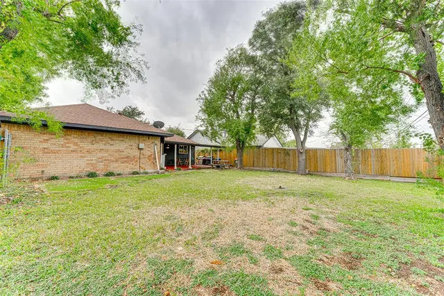 a view of a yard in front of a house with large trees
