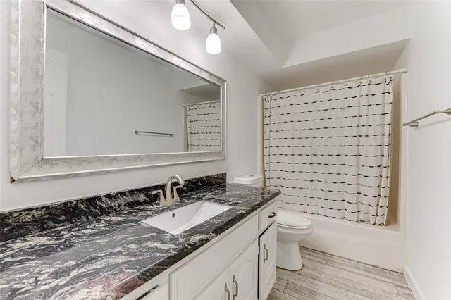 a bathroom with a granite countertop sink a toilet a mirror and shower
