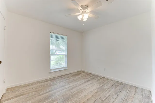 an empty room with a window and a ceiling fan