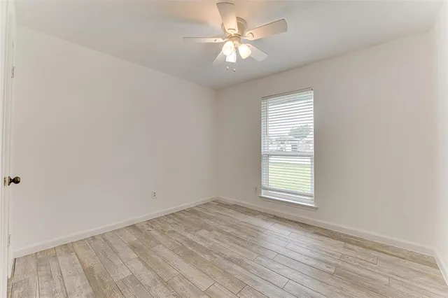 an empty room with a window and a fan