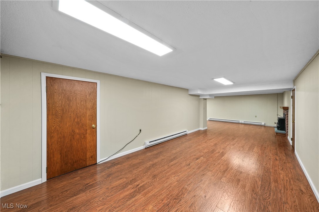 10 Kehner Road Mogadore, OH 44260 - Photo 22 of 32 Basement with a baseboard heating unit, a brick fireplace, and hardwood / wood-style flooring