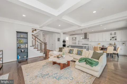 a kitchen with kitchen island a sink a stove a refrigerator and white cabinets with wooden floor