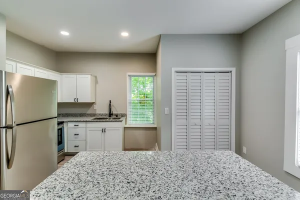 a kitchen with granite countertop a refrigerator a stove a sink and a window