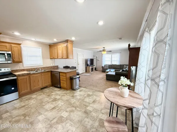 a kitchen with stainless steel appliances kitchen island granite countertop a stove a sink a refrigerator a dining table and chairs
