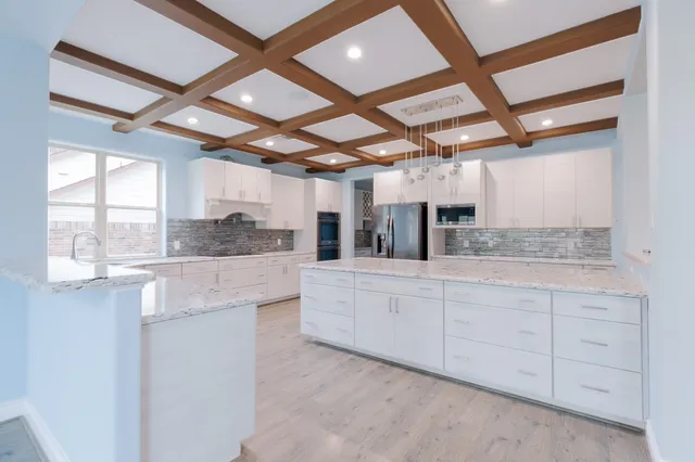 a large white kitchen with granite countertop a sink and dishwasher with white cabinets