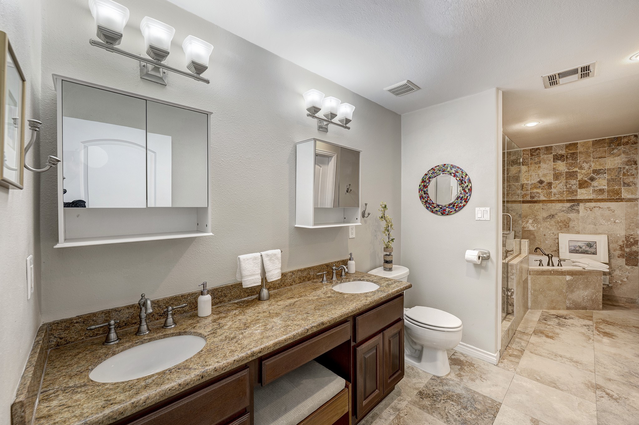 1111 Clovis Road Houston, TX 77008 - Photo 12 of 32 The primary bathroom features a granite dual vanity, travertine floors, a glass-enclosed shower with seat and a jetted tub. Floor-to-ceiling travertine lined walls encompasses the 'wet area'.