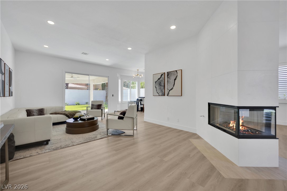 8981 Rivers Edge Drive Las Vegas, NV 89117 - Photo 10 of 69 A modern corner fireplace warms this inviting living space, connecting to a vibrant outdoor lawn through sliding glass doors.