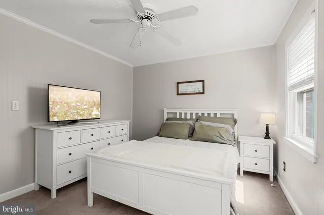 a bedroom with a bed and a flat tv screen on dresser