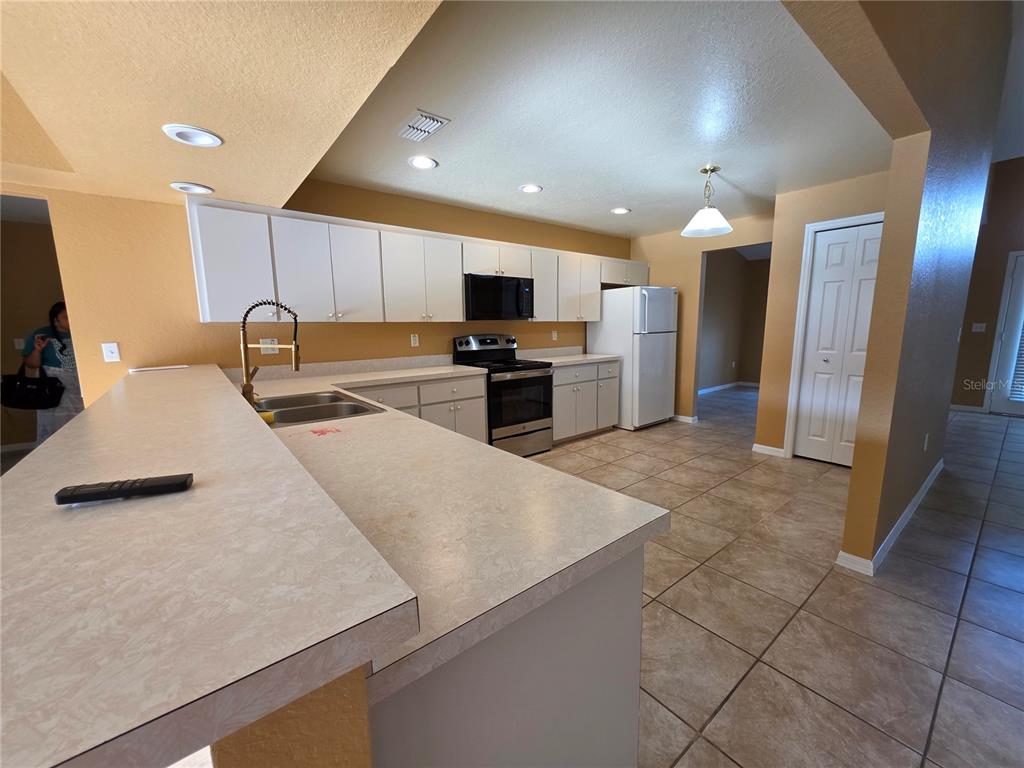 4532 Great Blue Heron Drive Lakeland, FL 33812 - Photo 13 of 33 a large kitchen with stainless steel appliances a large counter top a stove a refrigerator and a sink
