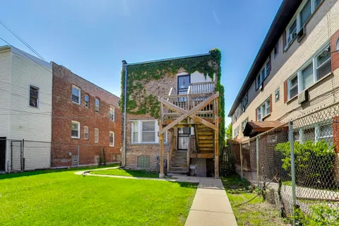 a backyard of a brick building with lawn chairs next to a yard