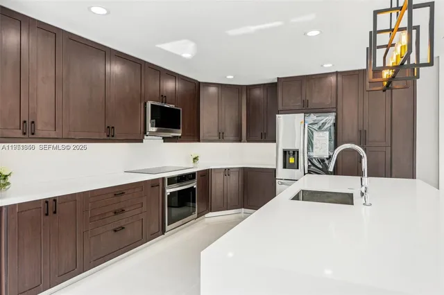 a kitchen with kitchen island stainless steel appliances a sink and a refrigerator