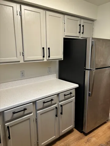 a view of a kitchen with refrigerator and white cabinets