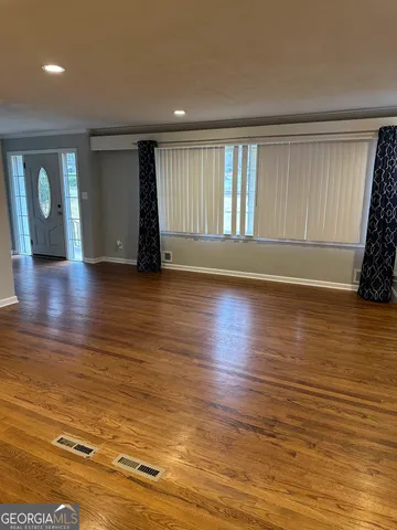 a view of an empty room with window and wooden floor