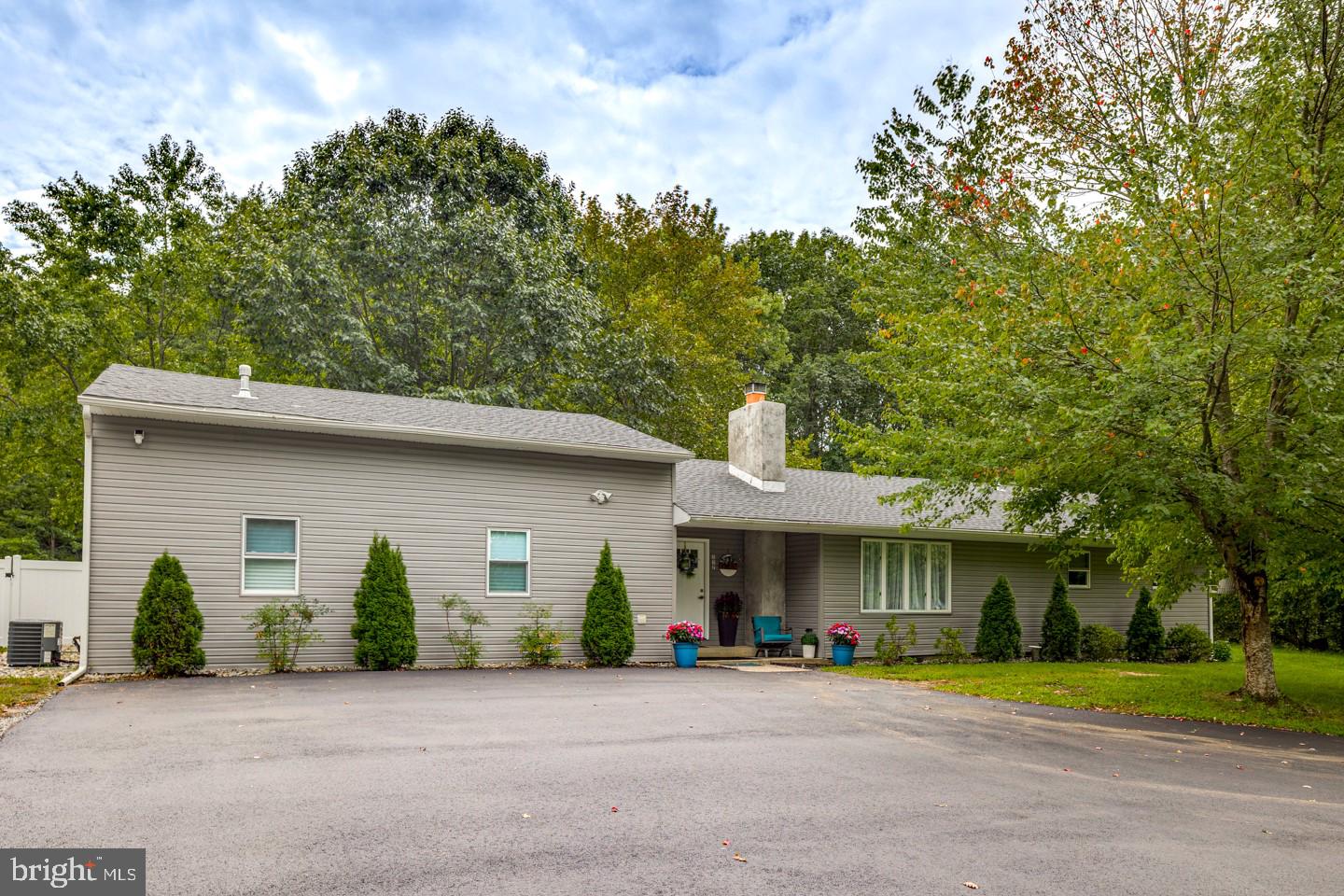 a front view of a house with a garden and trees