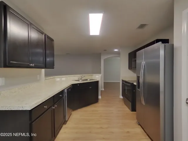 a kitchen with stainless steel appliances granite countertop a refrigerator a sink a stove and oven